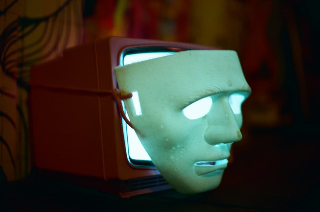 A mask covers a lit television screen.