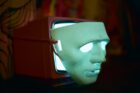 A mask covers a lit television screen.