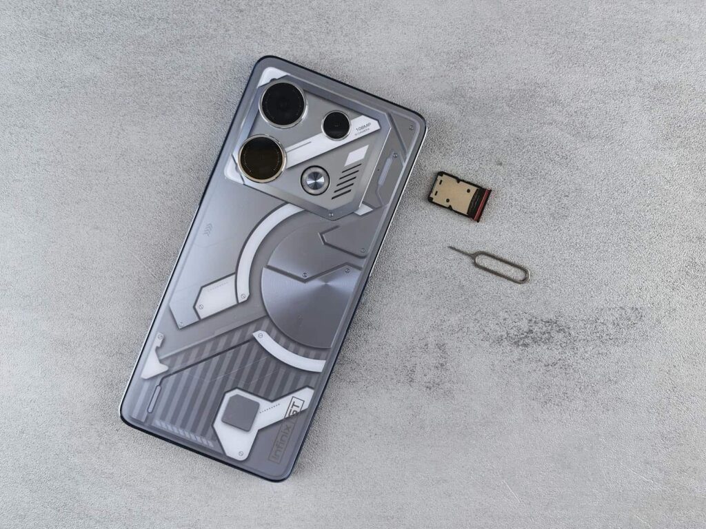 Close-up of a smartphone with futuristic design alongside a SIM card and ejector tool on a gray surface.