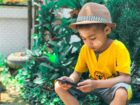 boy in yellow crew neck t-shirt and brown hat sitting on ground