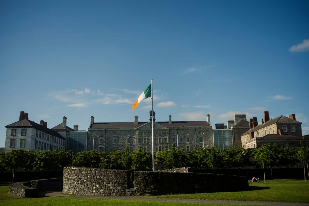 The irish flag flies in front of a large building.