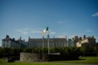 The irish flag flies in front of a large building.
