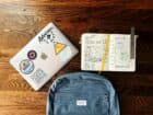 flat lay photography of blue backpack beside book and silver MacBook